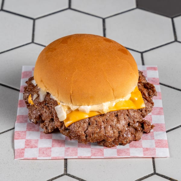 Smashed double cheeseburger with melted cheese, diced onions, and creamy sauce on a golden bun.