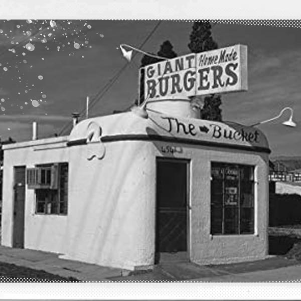 Black and white photo of "Giant Home Made Burgers The Bucket" restaurant building with a sign.